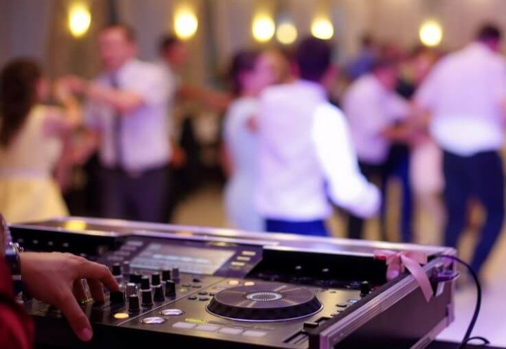 Régie DJ au premier plan, invités dansant en arrière-plan