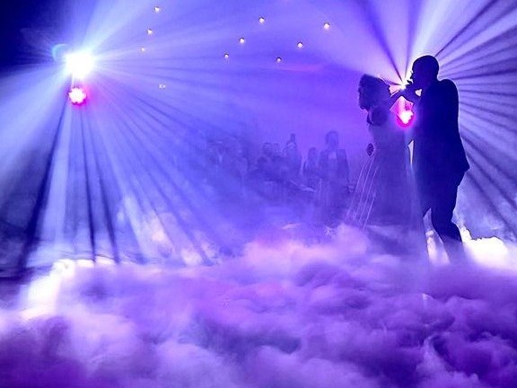 Ouverture de bal des mariés dans un nuage de fumée et faisceaux violets